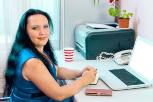 Brunetka w biurze domowym pracuje na laptopie, patrząc na fotoaparatu.