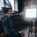 Mężczyzna w kasku z folii aluminiowej sięga do telewizora