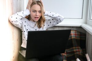 Młoda kobieta siedząca na balkonie obok laptopa krzycząc stres online edukacja zostań w domu koncepcja