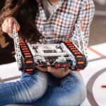 Ciesz się klasą techniczną. Zaangażowano utalentowaną małą dziewczynkę siedzącą w laboratorium robotyki i trzymającą szczegóły cyber robota podczas zajęć technicznych