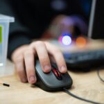zbliżenie ręki klikającej przyciski na myszy komputerowej