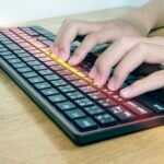 Zbliżenie męskich rąk piszących na czarnej klawiaturze Biznesmen pracuje nad efektem świetlnym