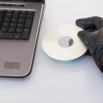 Włamywacz włamuje się i wkłada płytę CD-ROM do laptopa