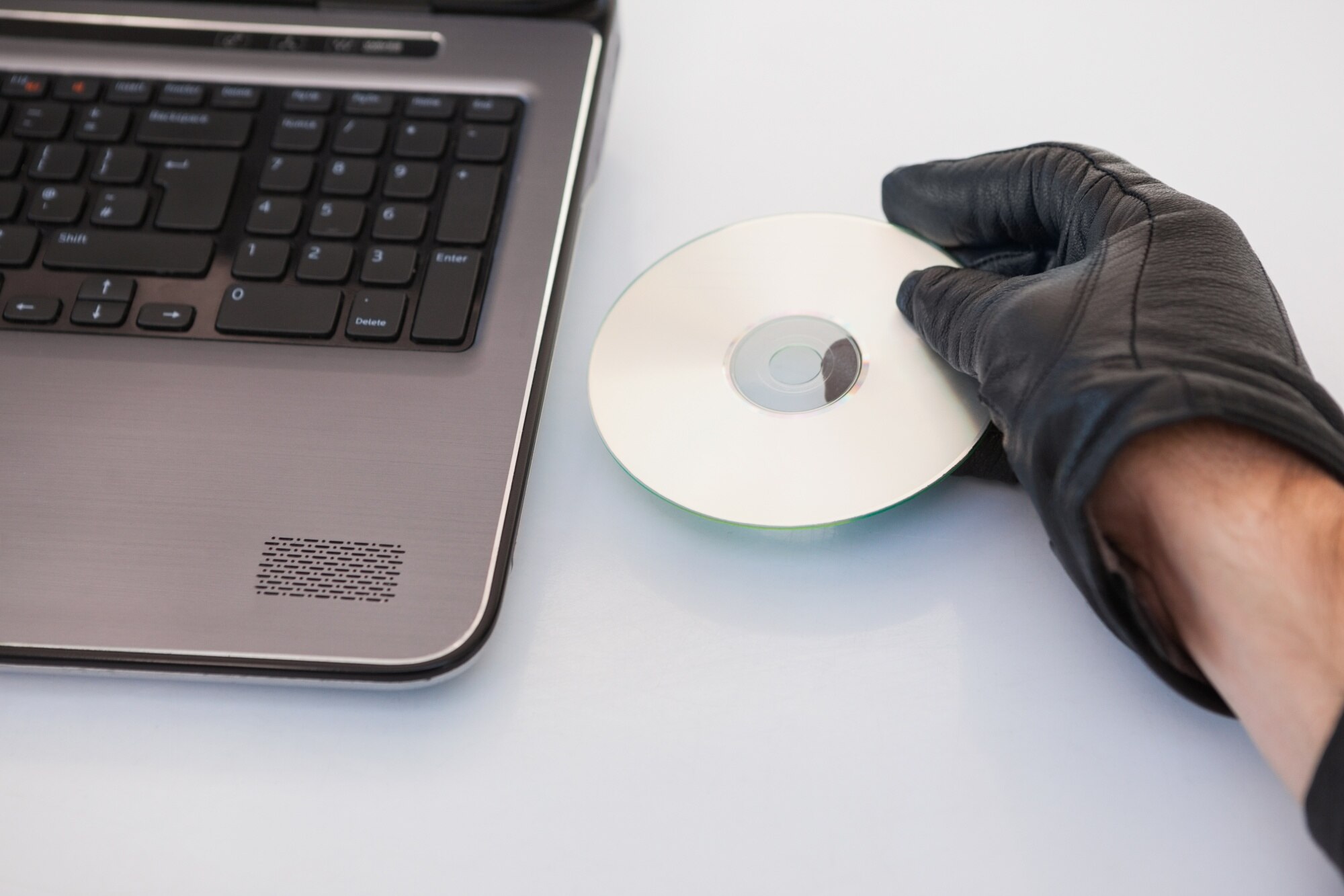 Włamywacz włamuje się i wkłada płytę CD-ROM do laptopa