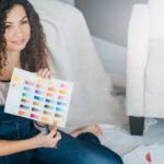 hobby sztuki. artystka siedząca zrelaksowana na podłodze z próbką koloru farby i ołówkami