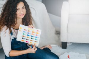 hobby sztuki. artystka siedząca zrelaksowana na podłodze z próbką koloru farby i ołówkami