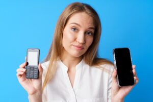 Młoda kobieta trzyma stary i nowy telefon na niebieskim tle