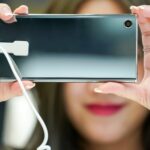 Młoda Azjatycka dziewczyna testuje i gra w nowy telefon komórkowy w sklepie z elektronicznymi telefonami komórkowymi.
