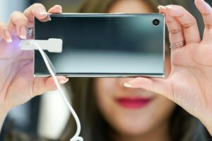 Młoda Azjatycka dziewczyna testuje i gra w nowy telefon komórkowy w sklepie z elektronicznymi telefonami komórkowymi.