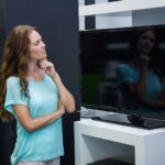 Ładna kobieta robi zakupy dla nowej telewizji