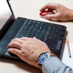 Mężczyzna w biurze piszący na klawiaturze laptopa Biznesmen w pracy Ręce z bliska