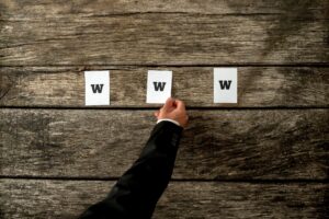 Wysoki kąt widzenia web developera umieszczającego trzy białe księgi pisowni WWW na teksturowanych rustykalnych drewnianych deskach. Koncepcyjne profesjonalistów internetowych w Internecie.