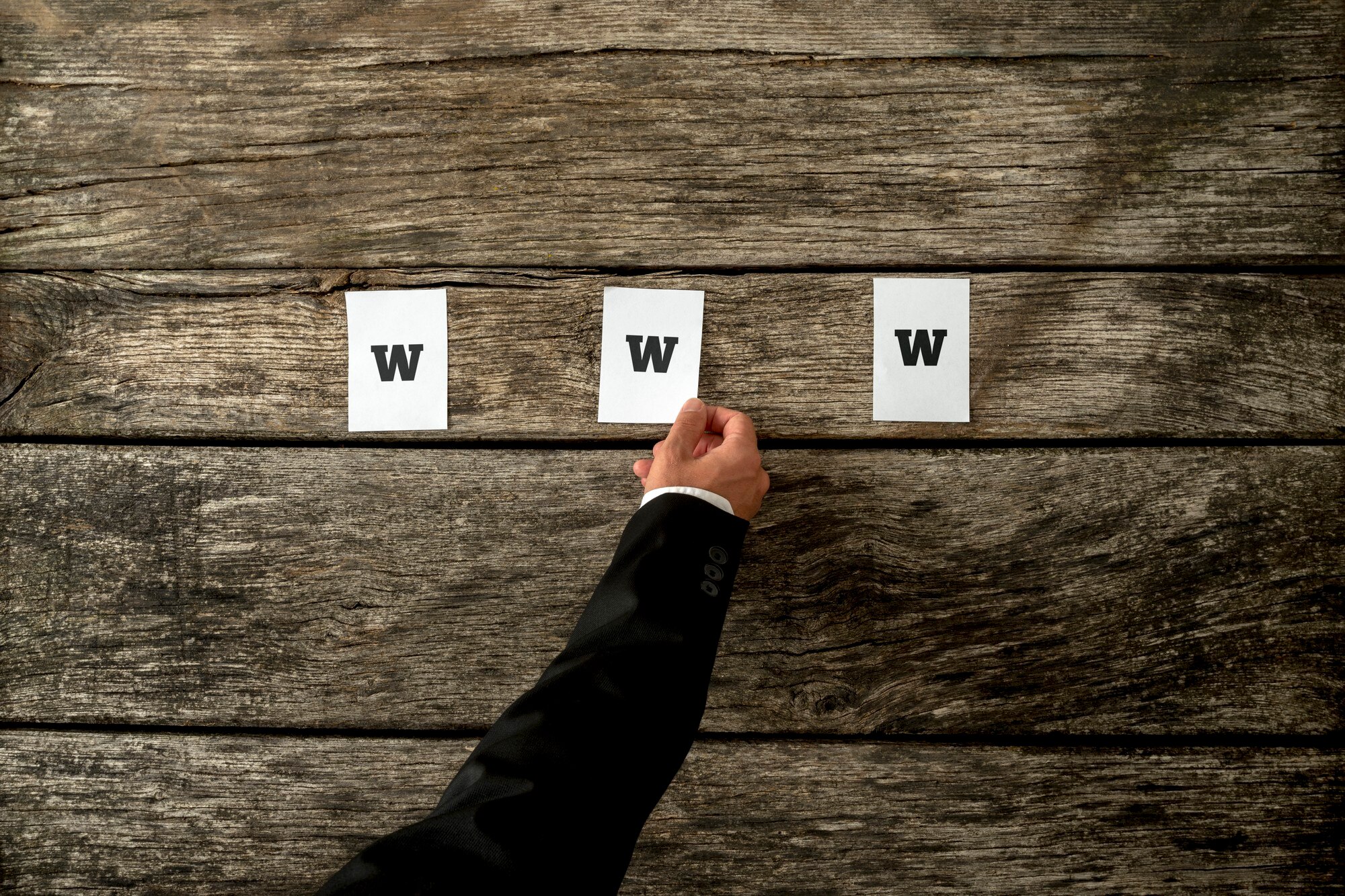 Wysoki kąt widzenia web developera umieszczającego trzy białe księgi pisowni WWW na teksturowanych rustykalnych drewnianych deskach. Koncepcyjne profesjonalistów internetowych w Internecie.
