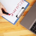 Kobieca ręka pisze CV szminką na białej kartce papieru