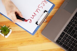 Kobieca ręka pisze CV szminką na białej kartce papieru