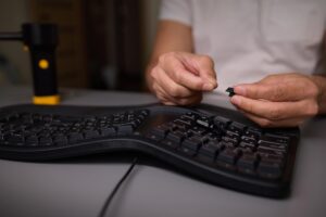 W zbliżeniu widać rękę używającą narzędzia wyciągającego klawisze do skrupulatnego usunięcia klawisza klawiatury