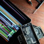 Złamany tablet i rozebrane smartfony z narzędziami naprawczymi