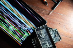 Złamany tablet i rozebrane smartfony z narzędziami naprawczymi