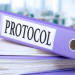 Protokół, tekst zapisany w teczce z dokumentami w modnym fioletowym kolorze, leżące na stosie papierów, dokumenty na biurowym biurku, na tle biurowego rozmytego miękkiego tła. Wysoka jakość ph