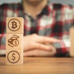 Symbole dolara wymiany bitcoinów na drewnianych kostkach w rękach Koncepcja kryptowaluty i gotówki w tle drewniany stół