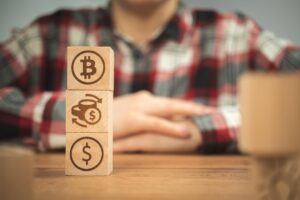 Symbole dolara wymiany bitcoinów na drewnianych kostkach w rękach Koncepcja kryptowaluty i gotówki w tle drewniany stół