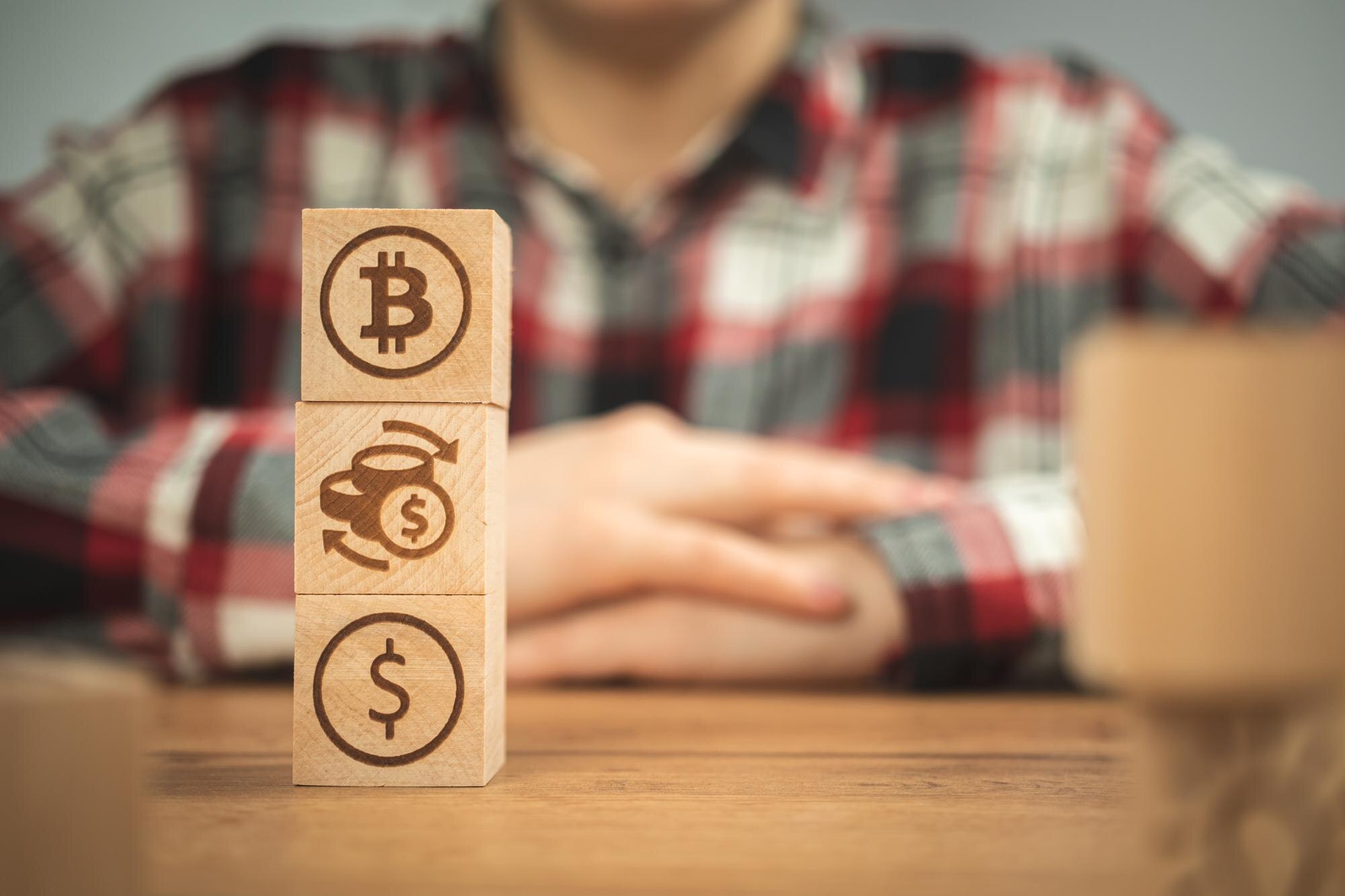 Symbole dolara wymiany bitcoinów na drewnianych kostkach w rękach Koncepcja kryptowaluty i gotówki w tle drewniany stół