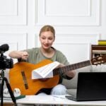 Elearning młoda śliczna piękna dziewczyna zdalnie prowadząca lekcje gry na gitarze w domu podekscytowana