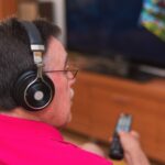 Tylny widok ogląda tv mienia pilot do tv starszy mężczyzna