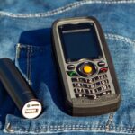 Telefon komórkowy i power bank na tle dżinsów w naturze