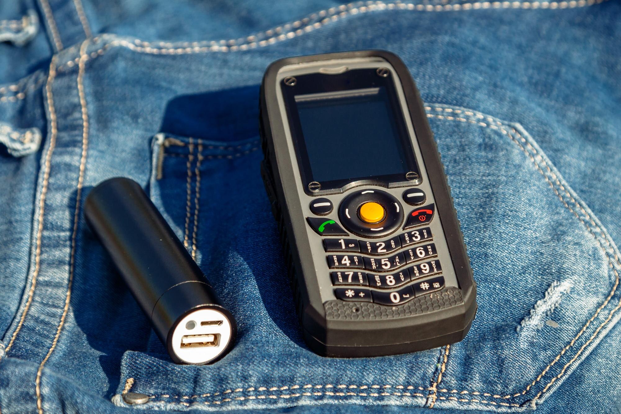 Telefon komórkowy i power bank na tle dżinsów w naturze