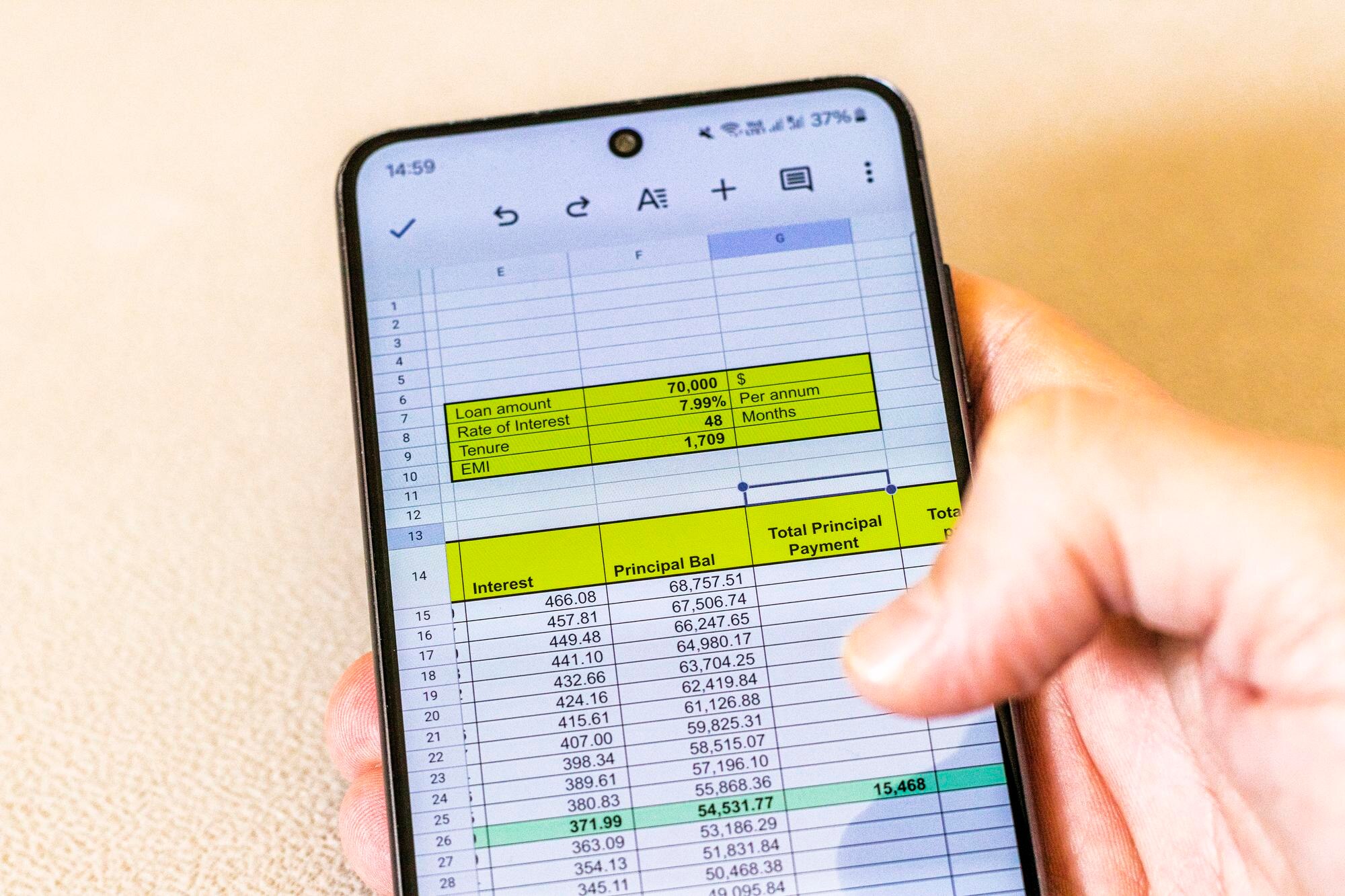 Mężczyzna przewracający arkusz Excel na ekranie telefonu pokazujący tabelę amortyzacji kredytów bankowych
