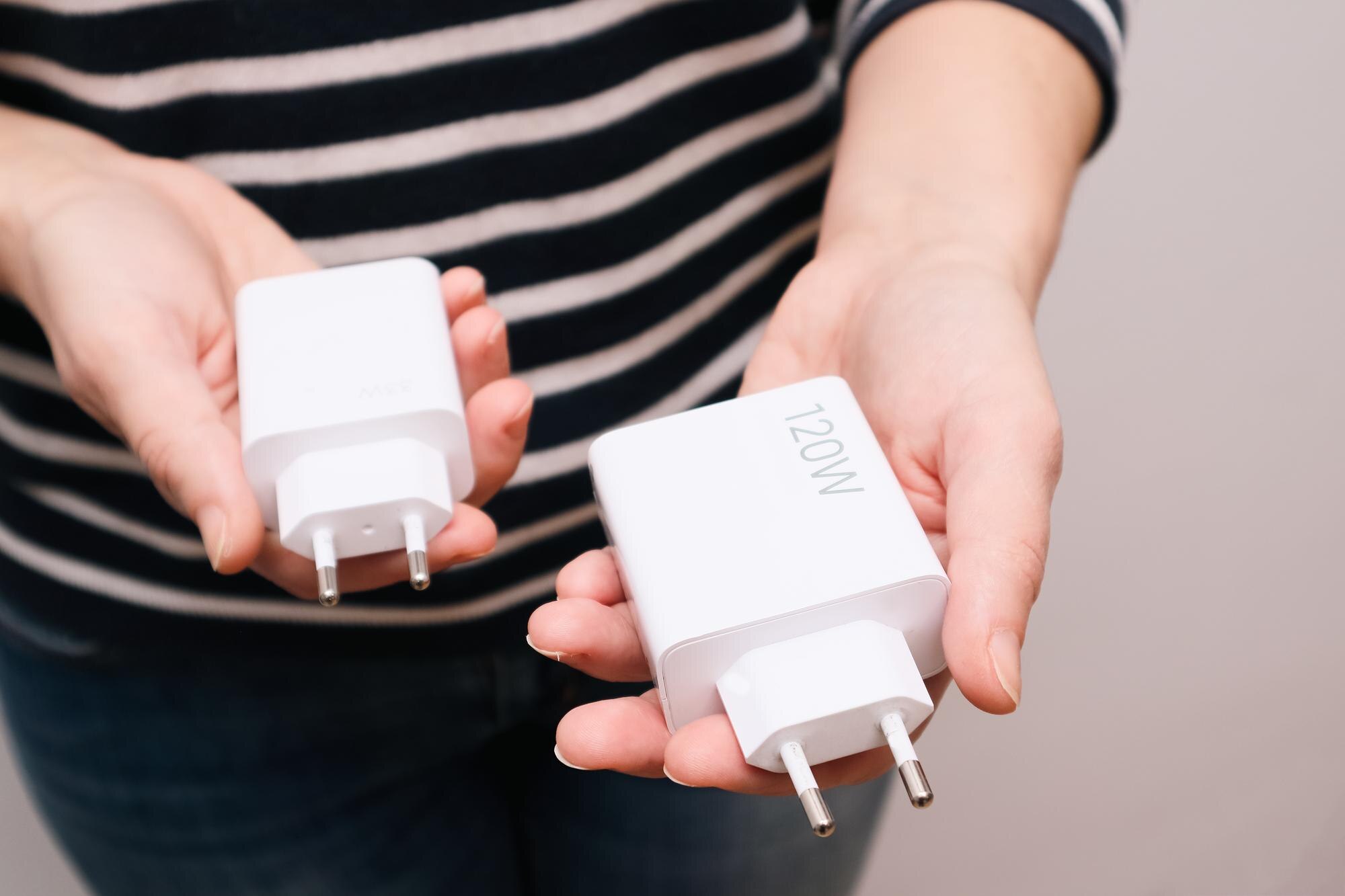 Potężne ładowarki USB do szybkiego ładowania smartfona w rękach kobiety Porównujemy rozmiary ładowarek o mocy 120 wattów i 33 wattów