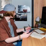 Teenage boy using tablet and taking notes at home desk