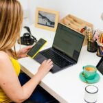 Koncepcja telepracy Młoda kobieta ubrana w żółtą koszulkę pracuje w domu