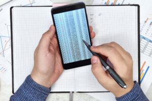 Ręce księgowego za pomocą telefonu komórkowego z raportem finansowym