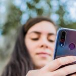 Ścieśniać Młoda kobieta sprawdza jej telefon komórkowy siedzi w parku Selektywne fokus Skoncentruj się na smartfonie