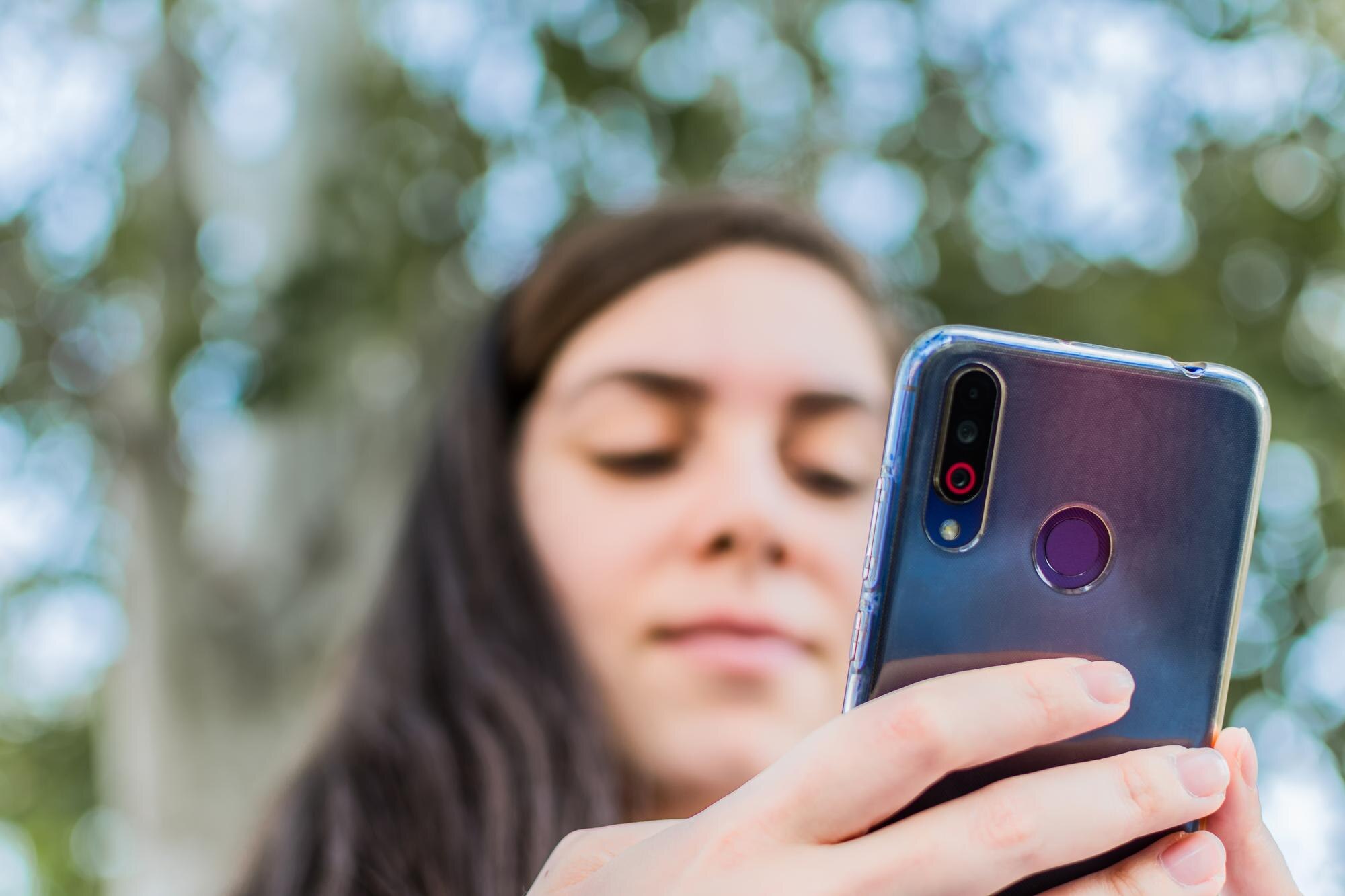 Ścieśniać Młoda kobieta sprawdza jej telefon komórkowy siedzi w parku Selektywne fokus Skoncentruj się na smartfonie