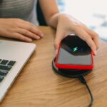 Ładowanie baterii telefonu komórkowego za pomocą urządzenia bezprzewodowego w stole Ładowanie smartfonu na poduszce ładującej Telefon komórkowy w pobliżu ładowarki bezprzewodowej