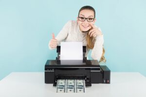 atrakcyjna szczęśliwa kobieta w swetrze i okularach gospodarstwa drukarki drukowania banknotów dolarowych z kciukiem do góry