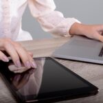 Brzuch kaukaskiej bizneswoman za pomocą laptopa i tabletu, odizolowany na szarym tle. koncepcja biznesu, technologii, komunikacji i wzrostu.