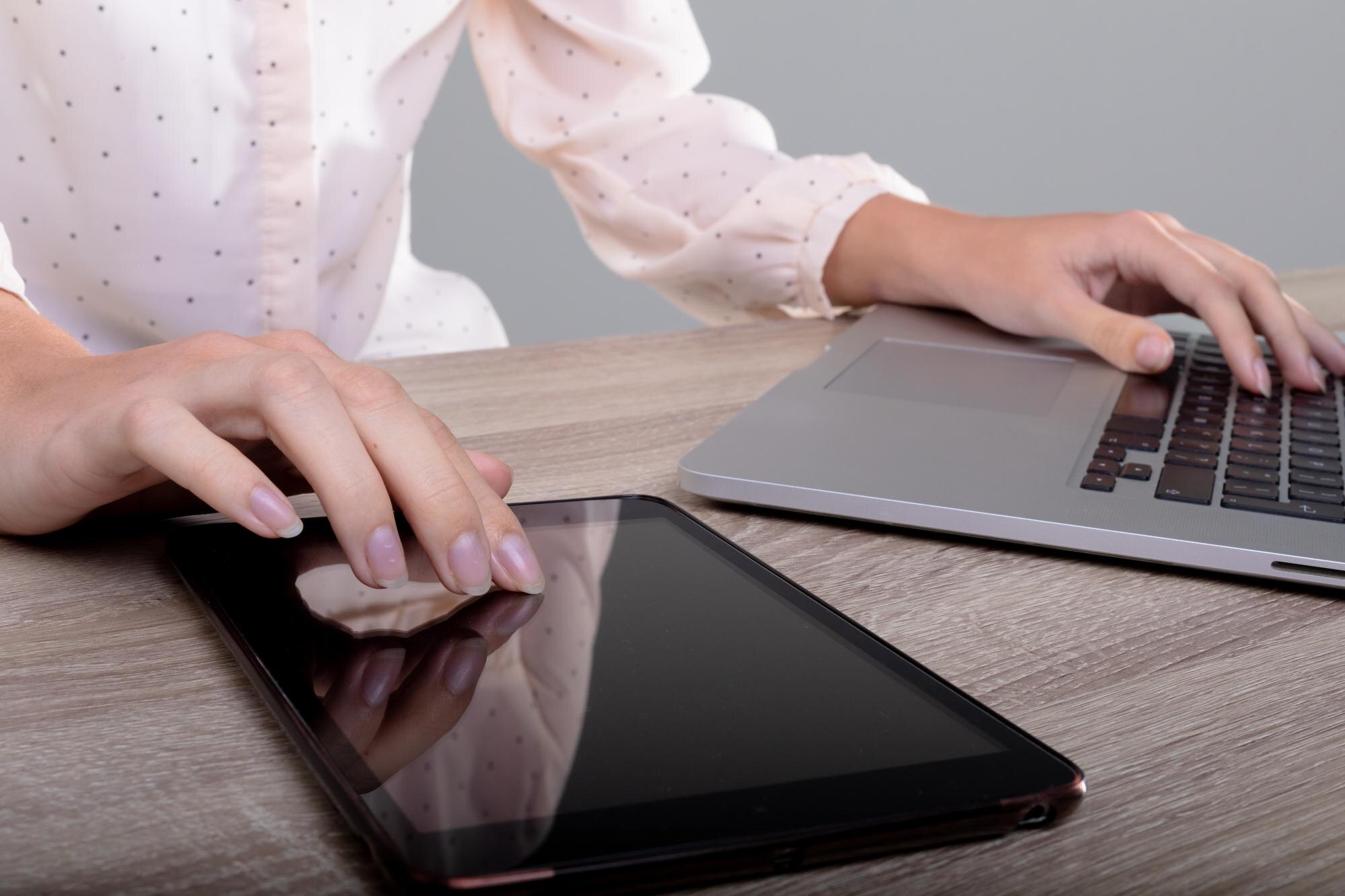Brzuch kaukaskiej bizneswoman za pomocą laptopa i tabletu, odizolowany na szarym tle. koncepcja biznesu, technologii, komunikacji i wzrostu.
