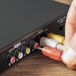 Zbliżenie dłoni łączącej wtyczkę z kolorowym wzmacniaczem muzycznym